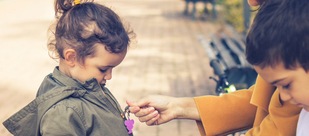 Mother zipping up daughter's jacket. Little girl's mother helping her to get dressed and zipping her coat.